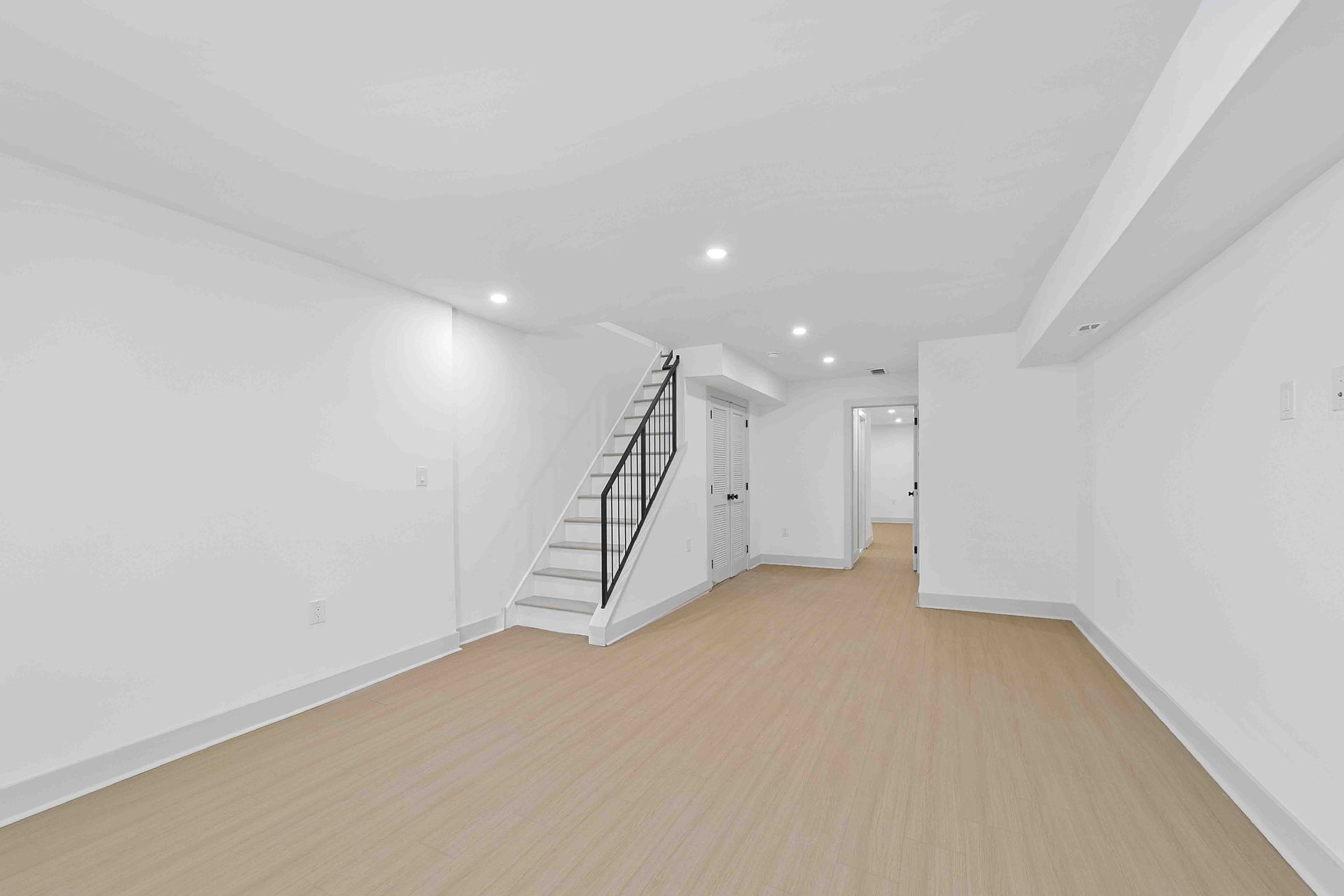 An empty basement with stairs leading up to the second floor.