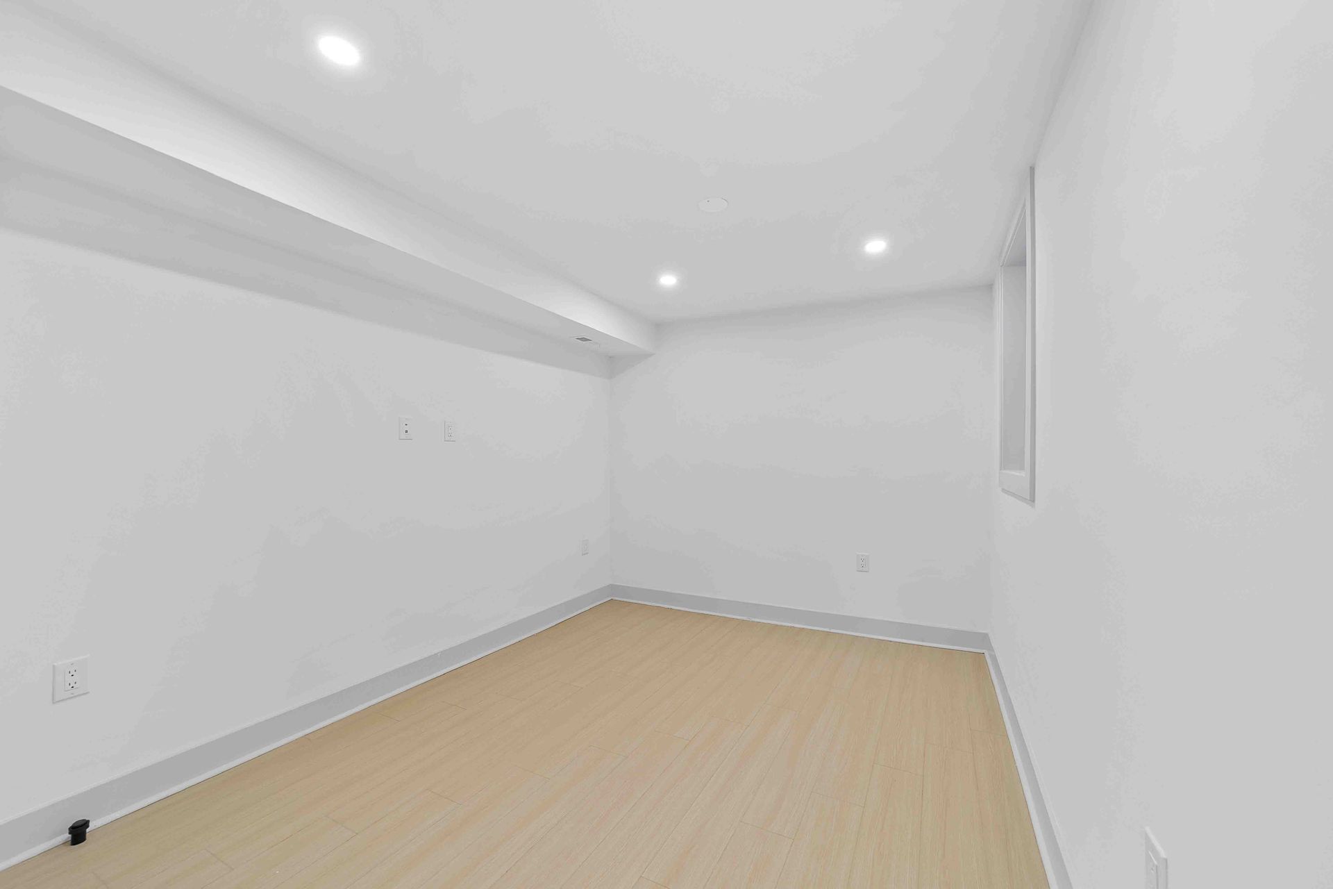 An empty room with white walls and a wooden floor.