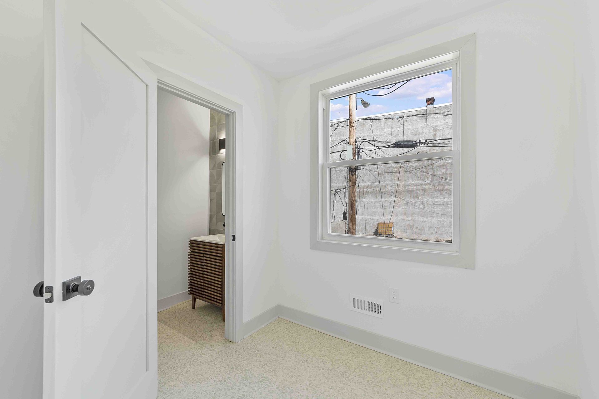 An empty room with a window and a door leading to a bathroom.