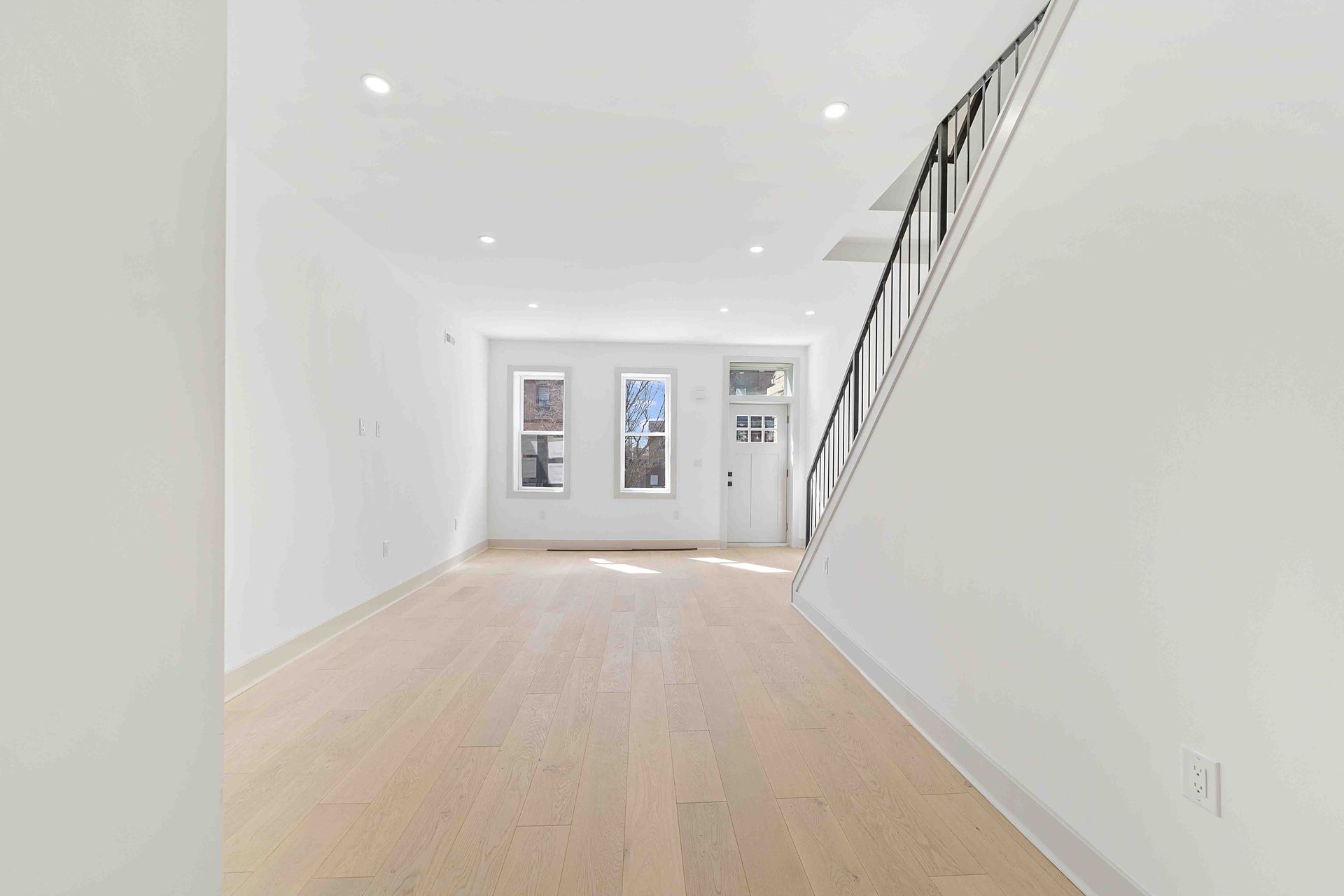 An empty room with hardwood floors and stairs in a house.