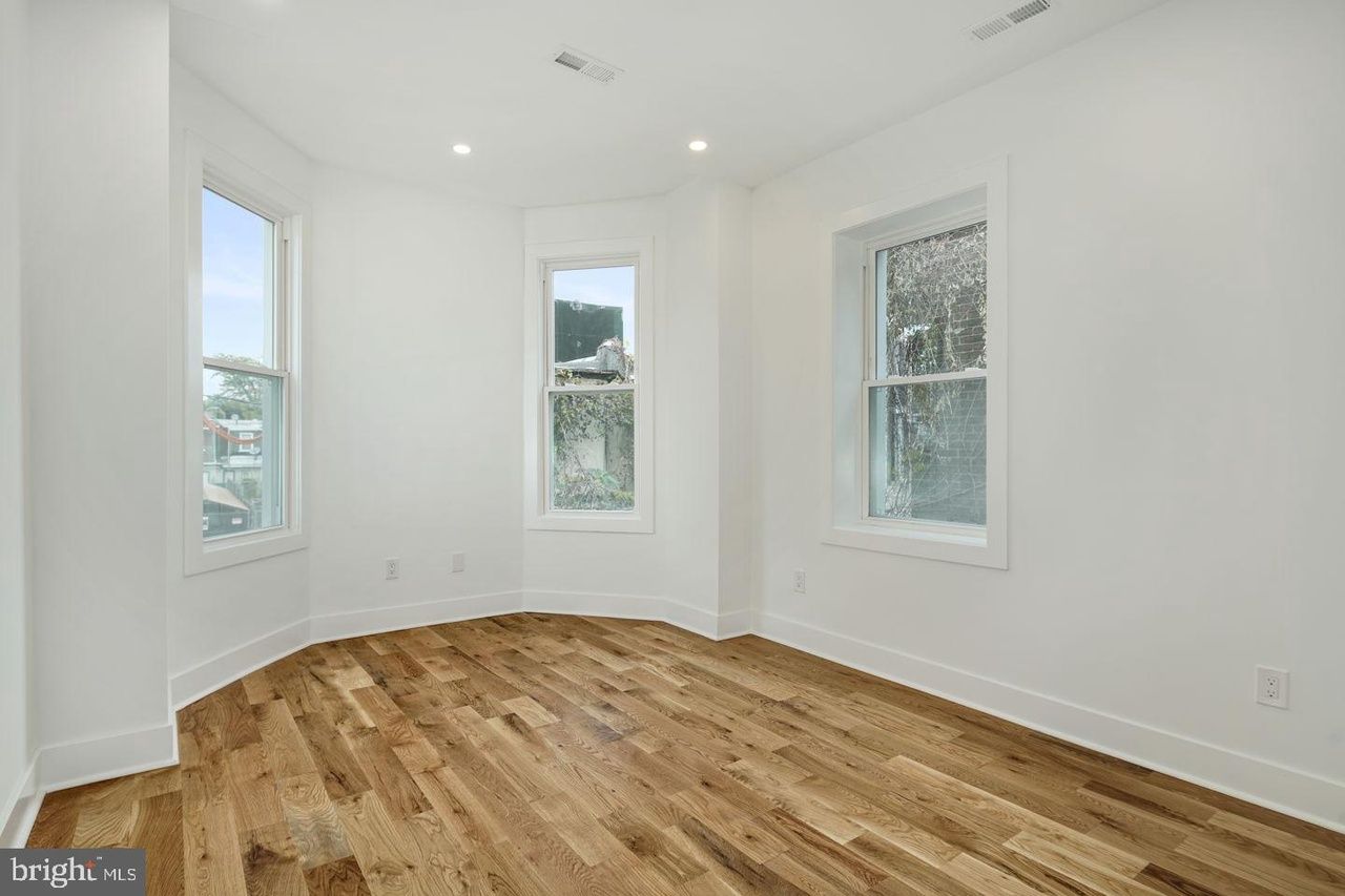 An empty room with hardwood floors and white walls.
