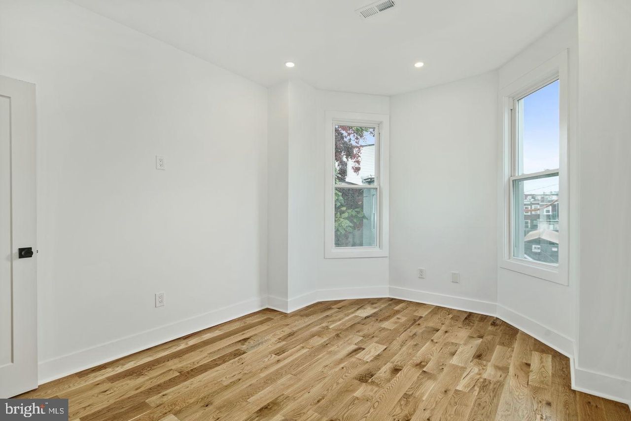 An empty room with hardwood floors and white walls.