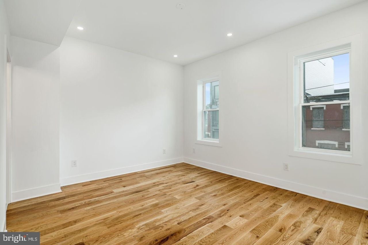An empty room with hardwood floors and white walls.