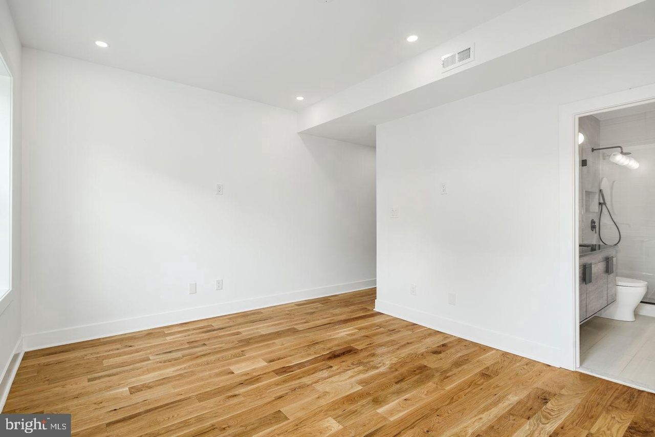 An empty room with hardwood floors and white walls.