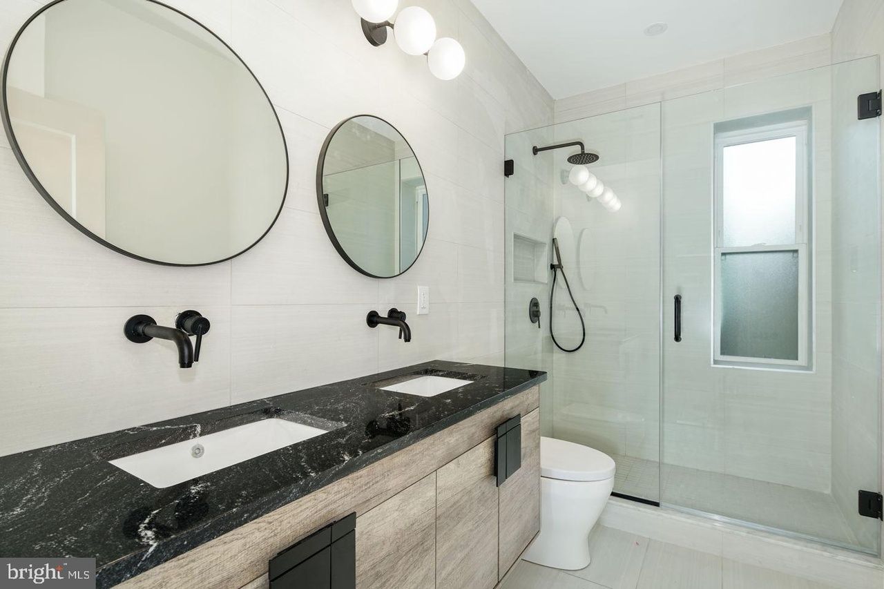 A bathroom with two sinks , a toilet and a shower.