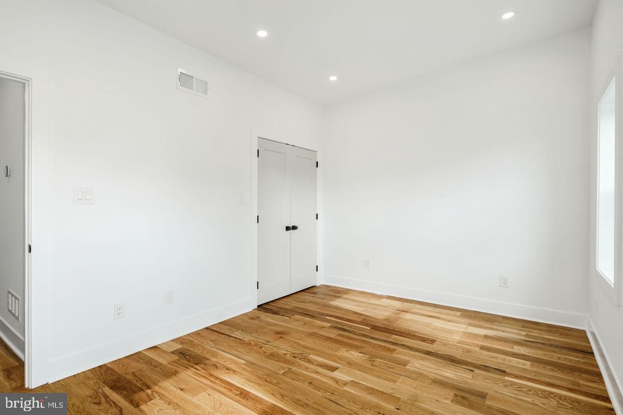 An empty room with hardwood floors and white walls.