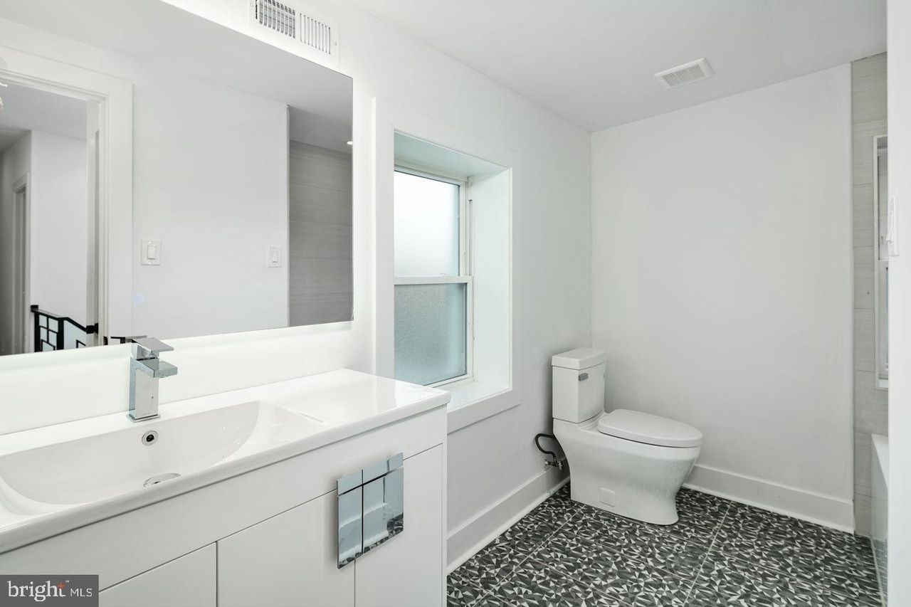 A bathroom with a toilet , sink and mirror.