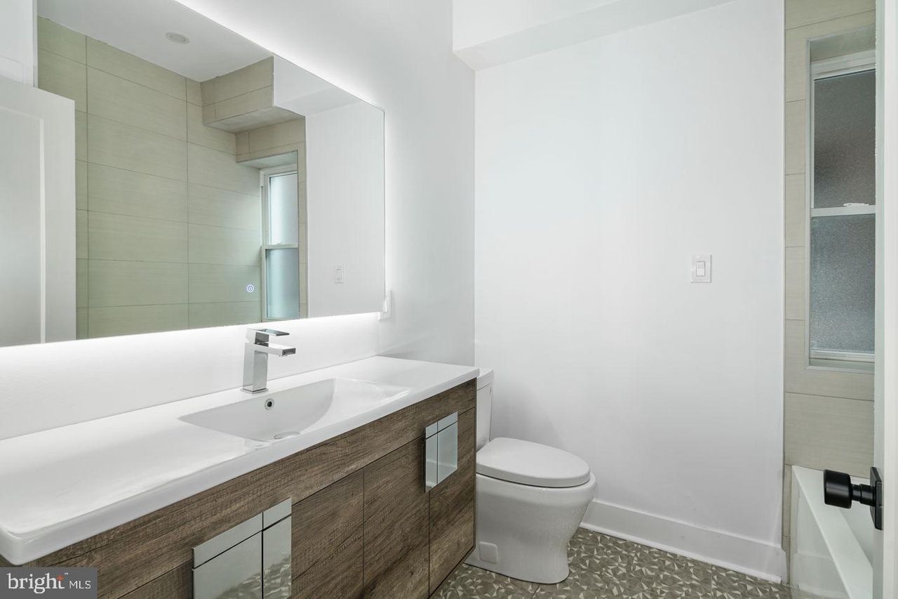 A bathroom with a sink , toilet and mirror.