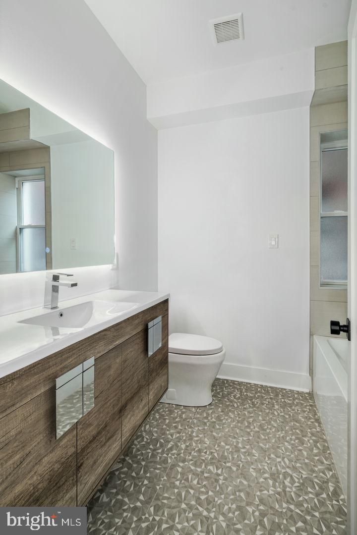 A bathroom with a toilet , sink and mirror.