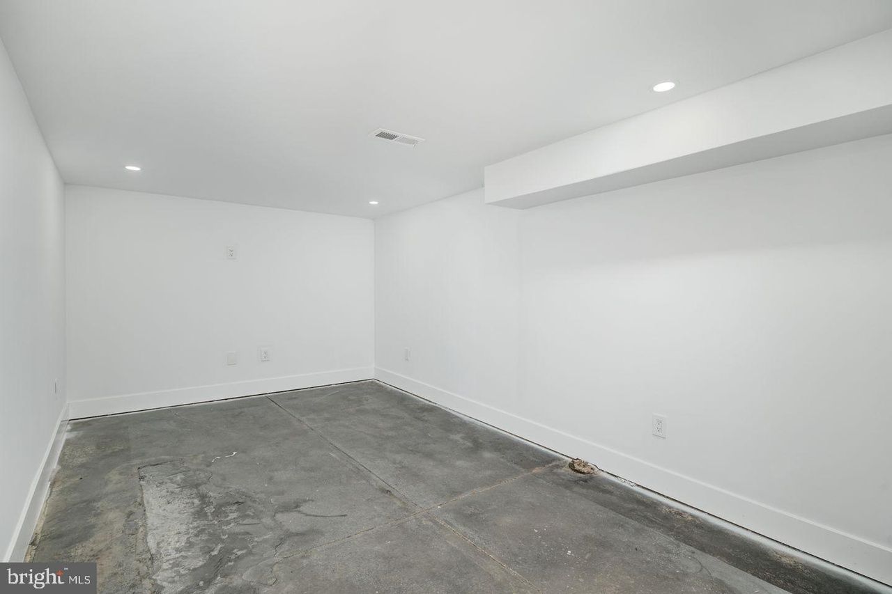 An empty basement with white walls and a gray carpet.