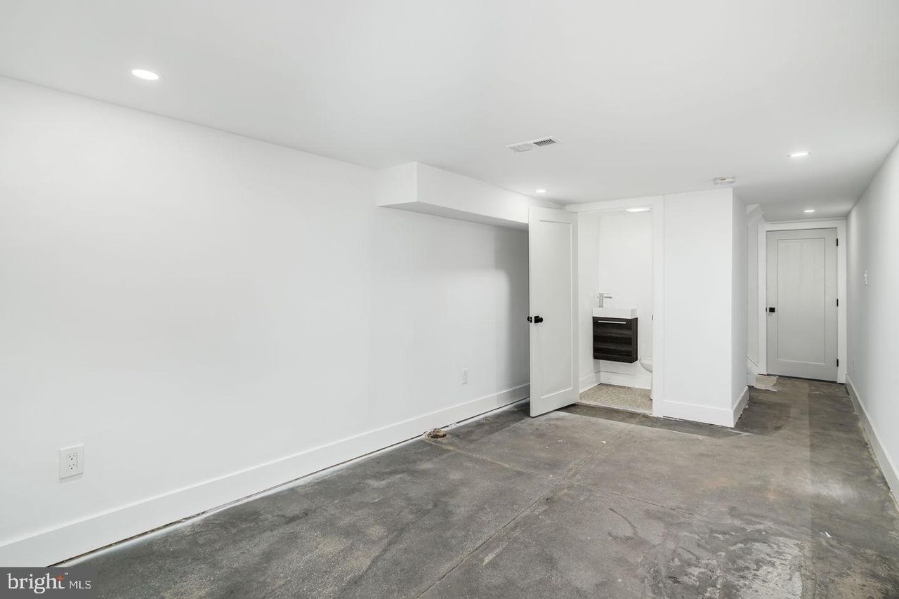 An empty basement with white walls and a gray carpet.