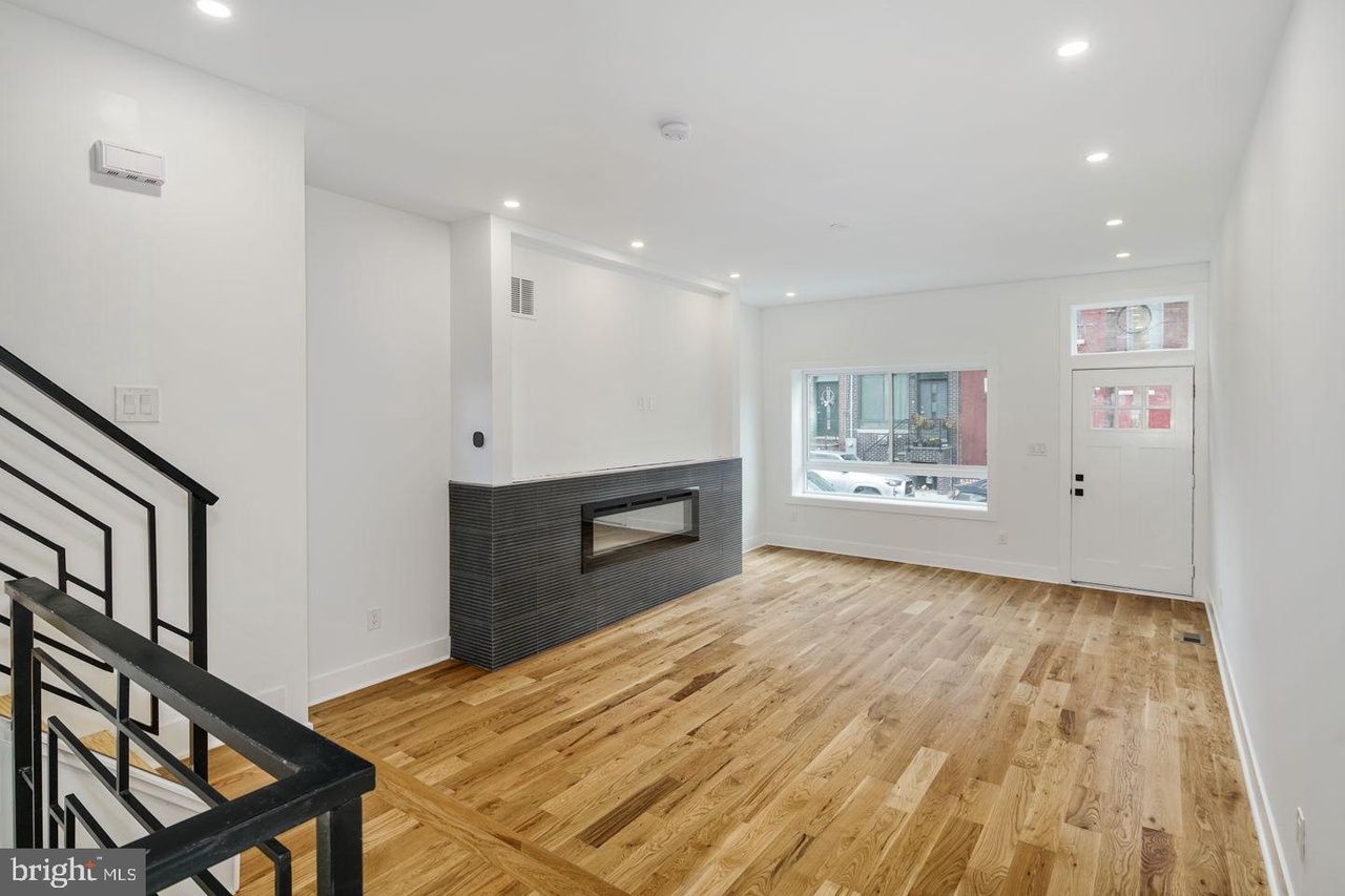 An empty living room with hardwood floors and a fireplace.