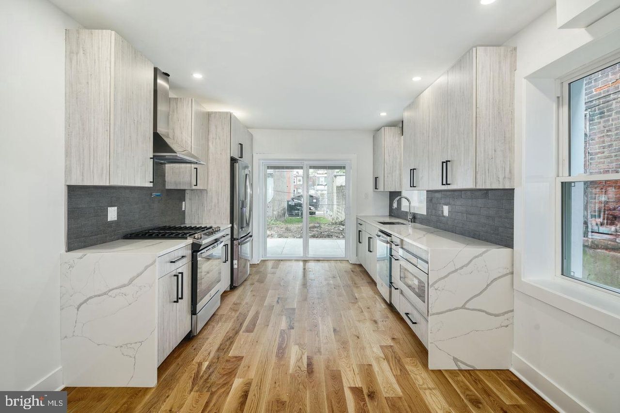 A kitchen with white cabinets , stainless steel appliances , and hardwood floors.