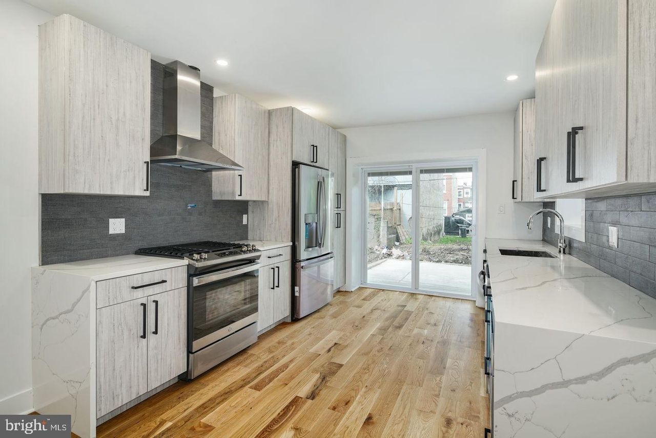 A kitchen with white cabinets , stainless steel appliances , and hardwood floors.