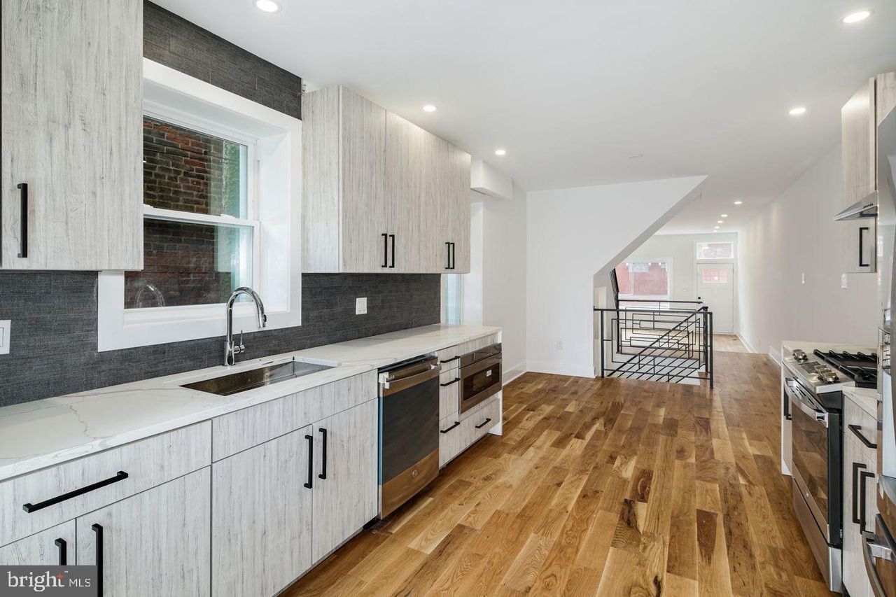 A kitchen with white cabinets , stainless steel appliances , and hardwood floors.