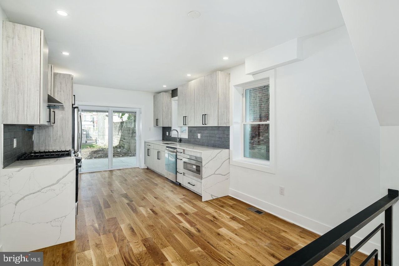 A kitchen and living room in a house with hardwood floors and white cabinets.