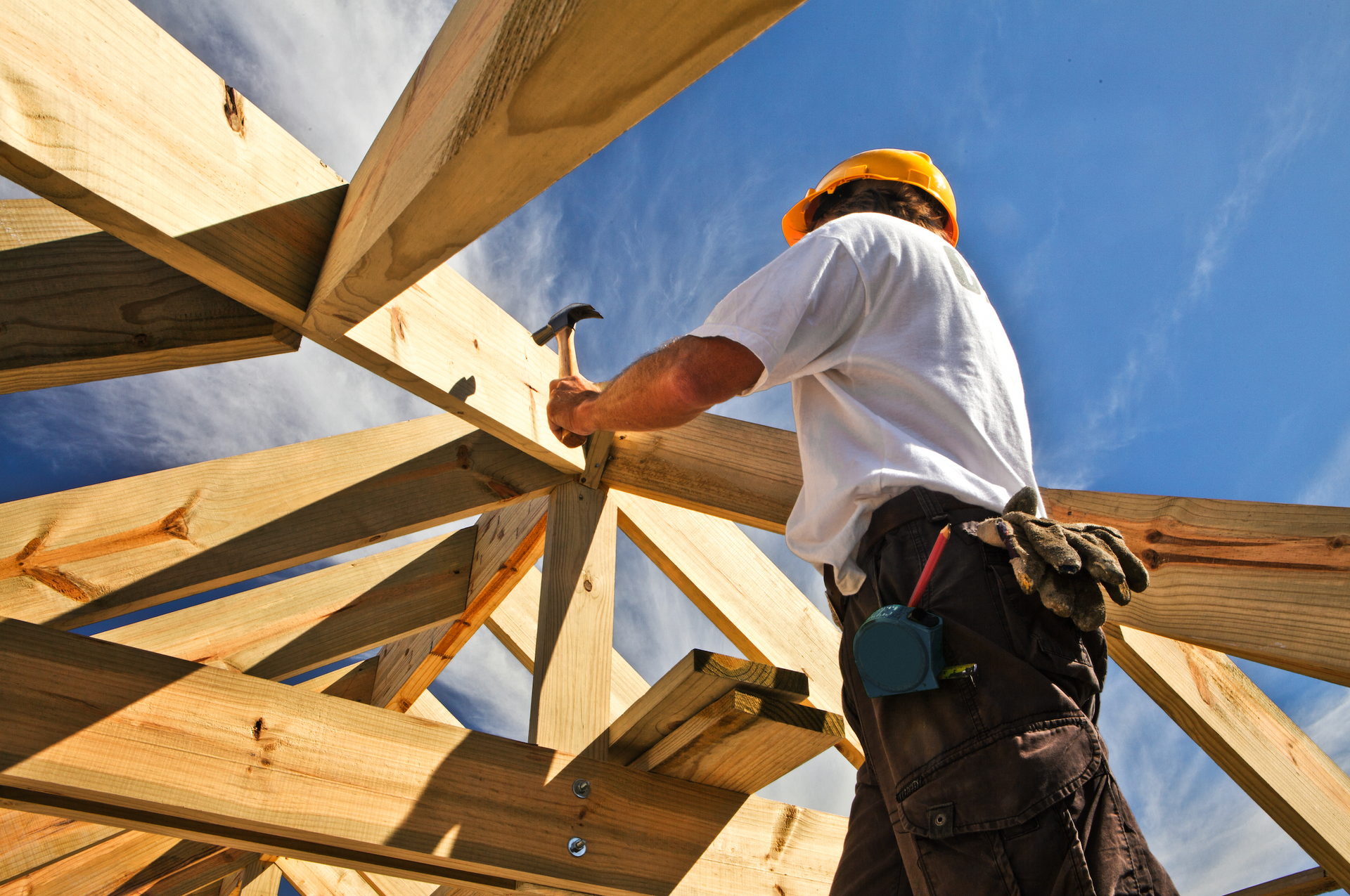 A man is working on a wooden structure with a hammer.