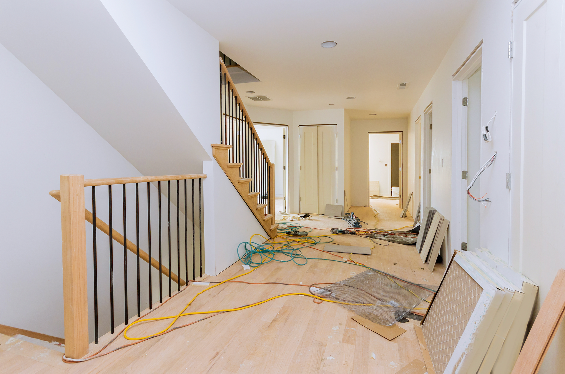 A hallway in a house under construction with wooden floors and stairs.