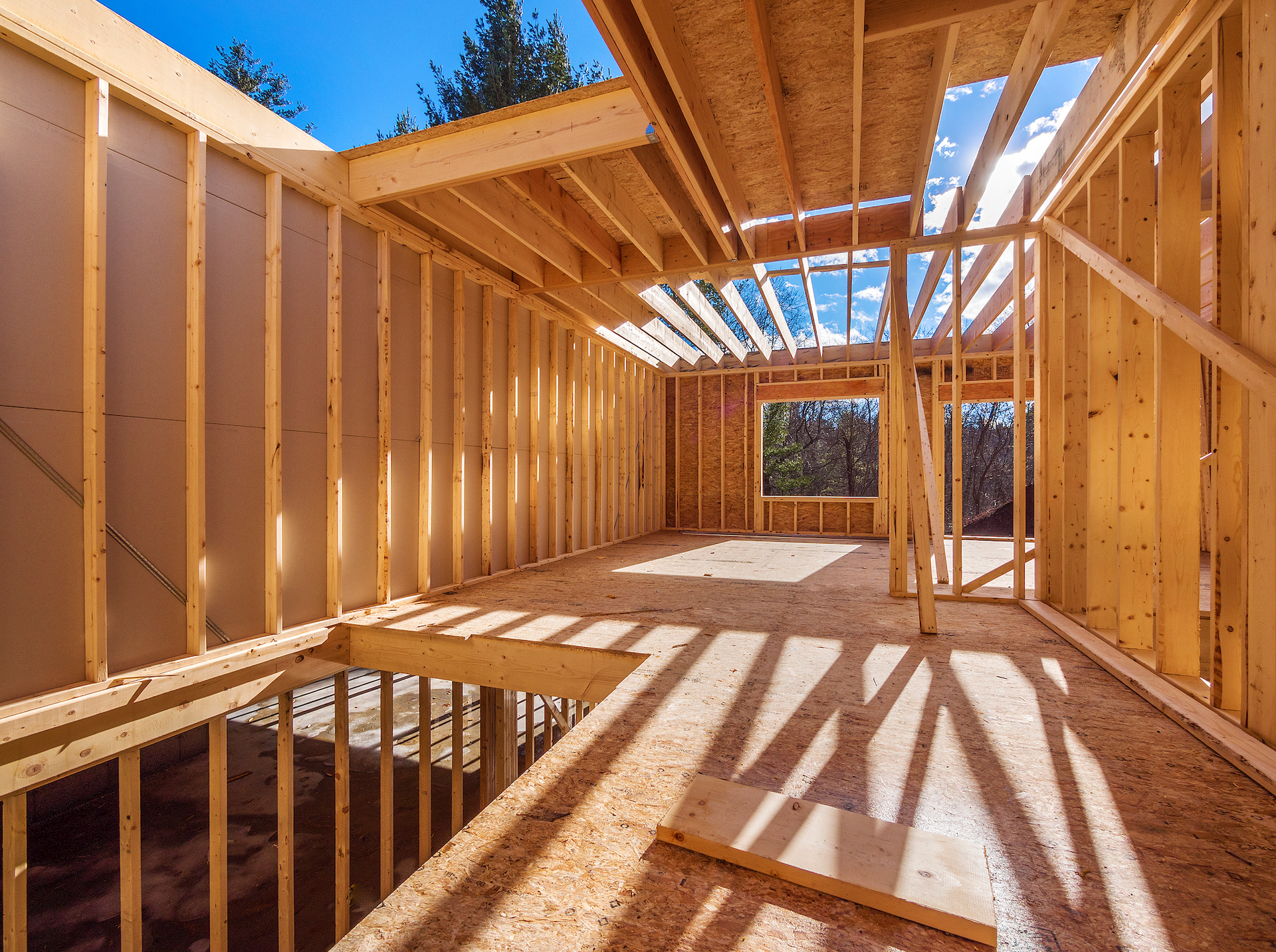The inside of a house under construction with wooden walls and a window.