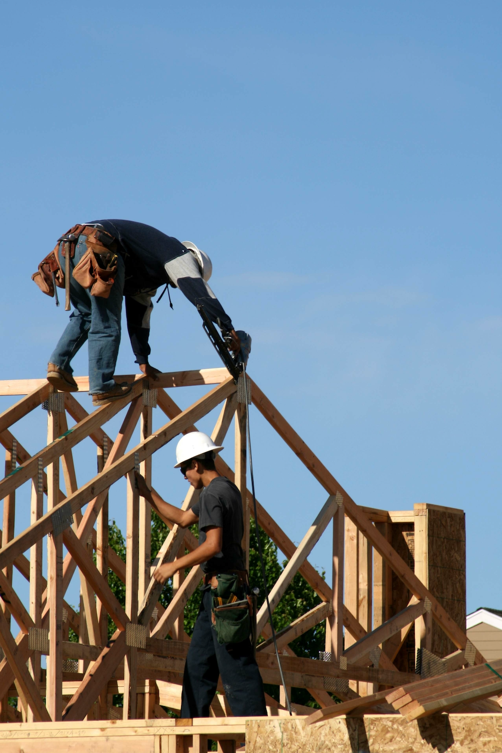 Two construction workers are working on a wooden structure