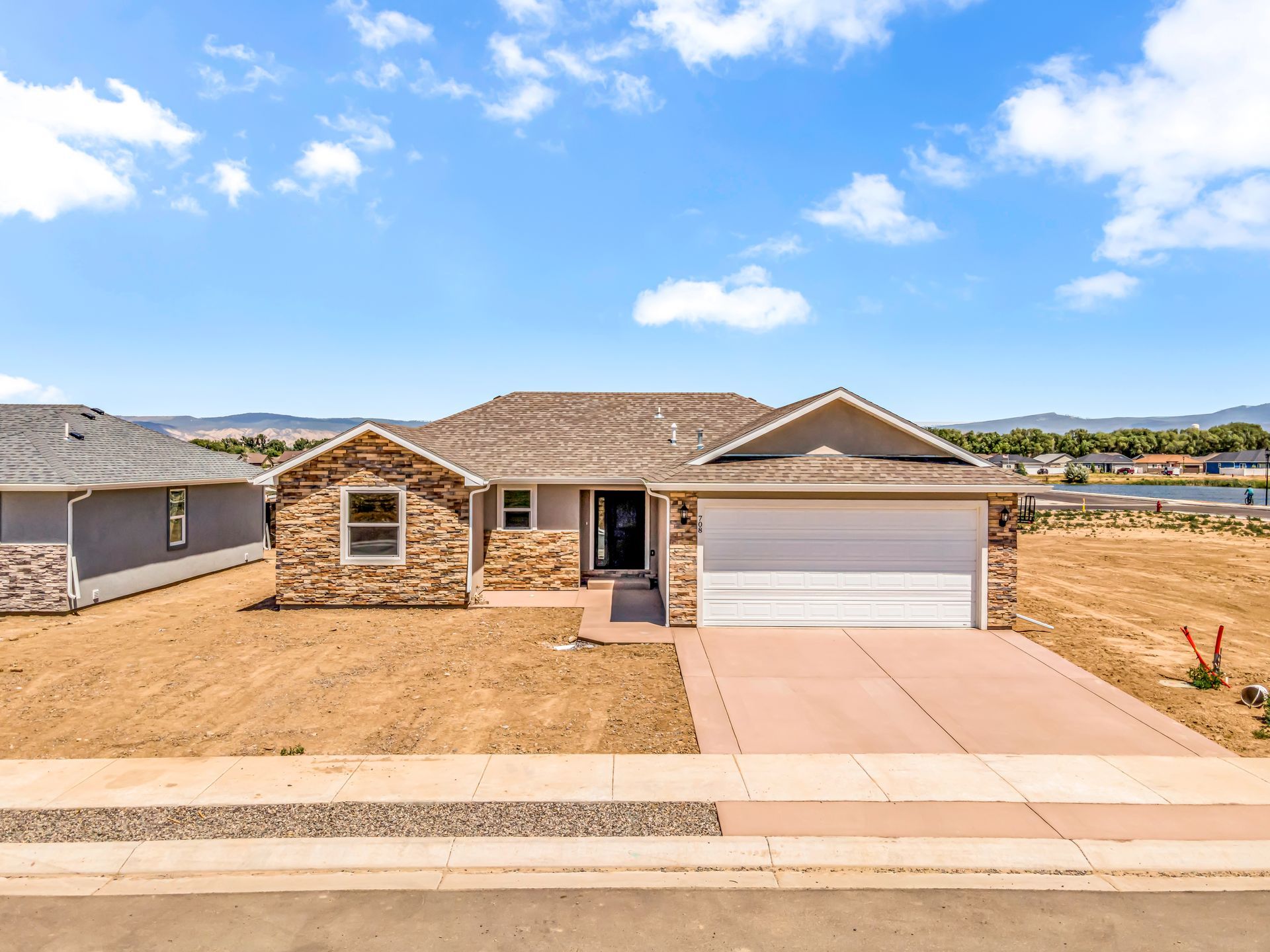 A house with a large garage and a lot of dirt in front of it.