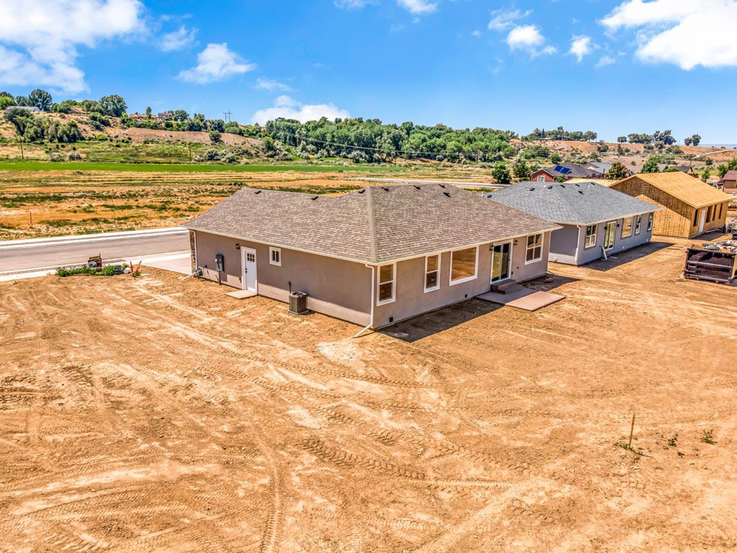 An aerial view of a house under construction in a dirt field.