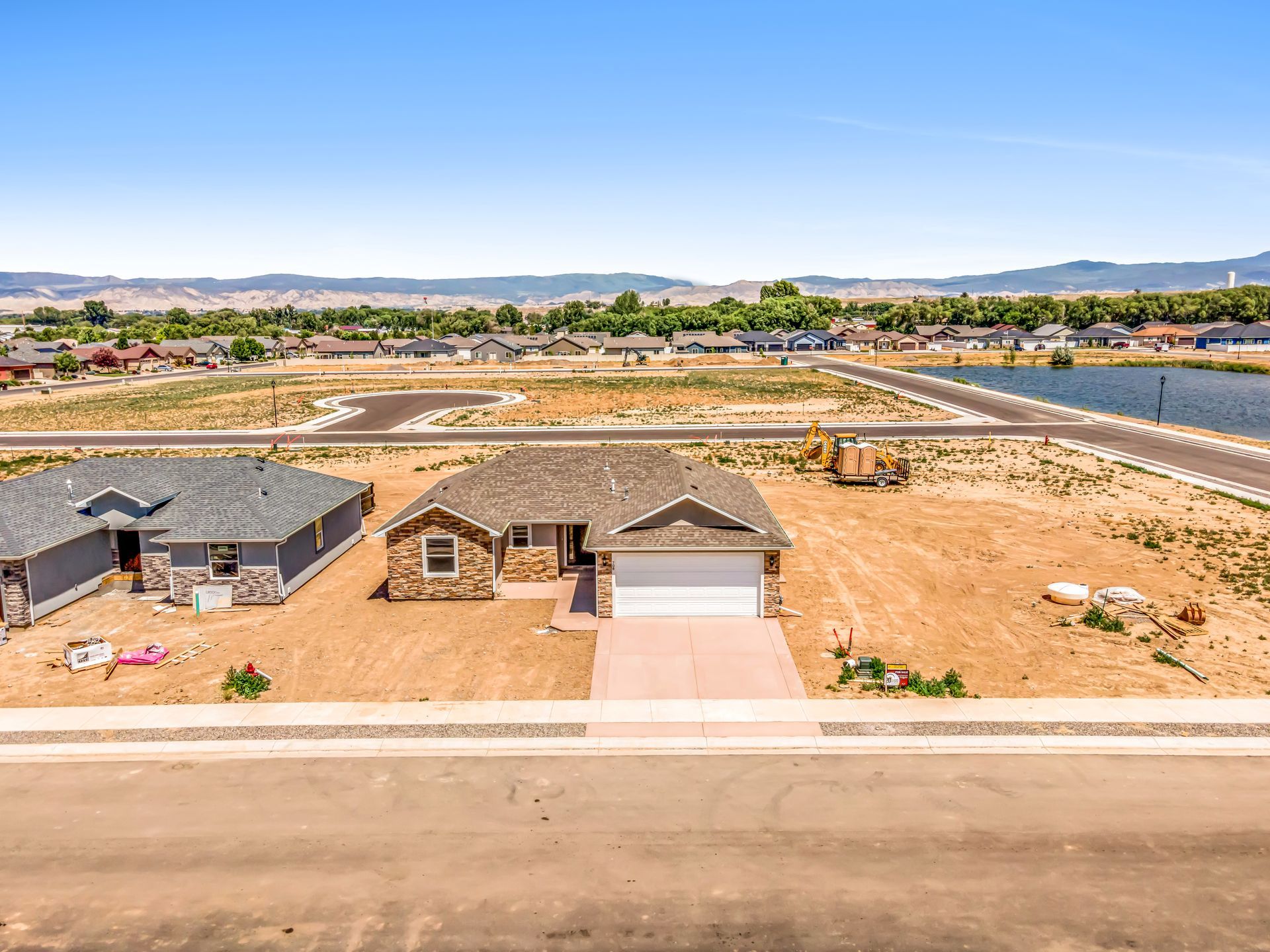 An aerial view of a house in a residential area with a lake in the background.