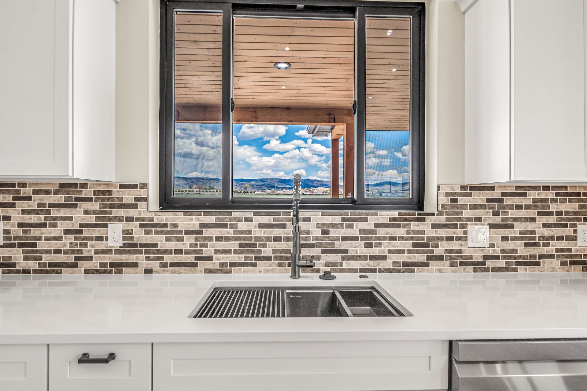 A kitchen with a sink and a window with a view of the ocean.