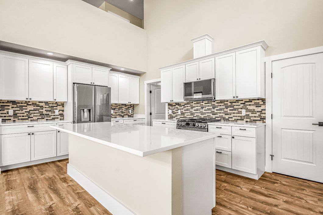 A kitchen with white cabinets , stainless steel appliances , and a large island.