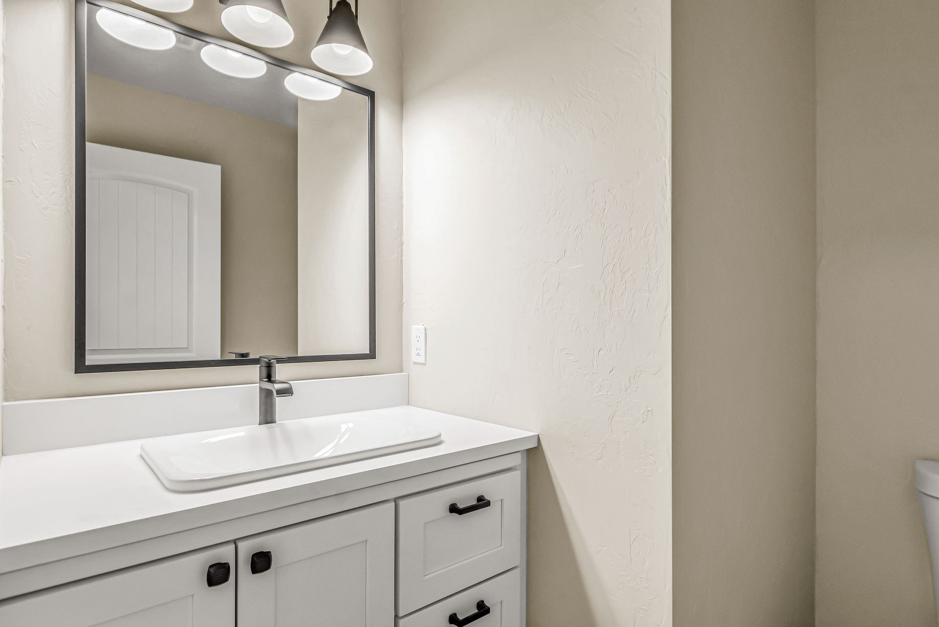 A bathroom with a sink , mirror and lights.