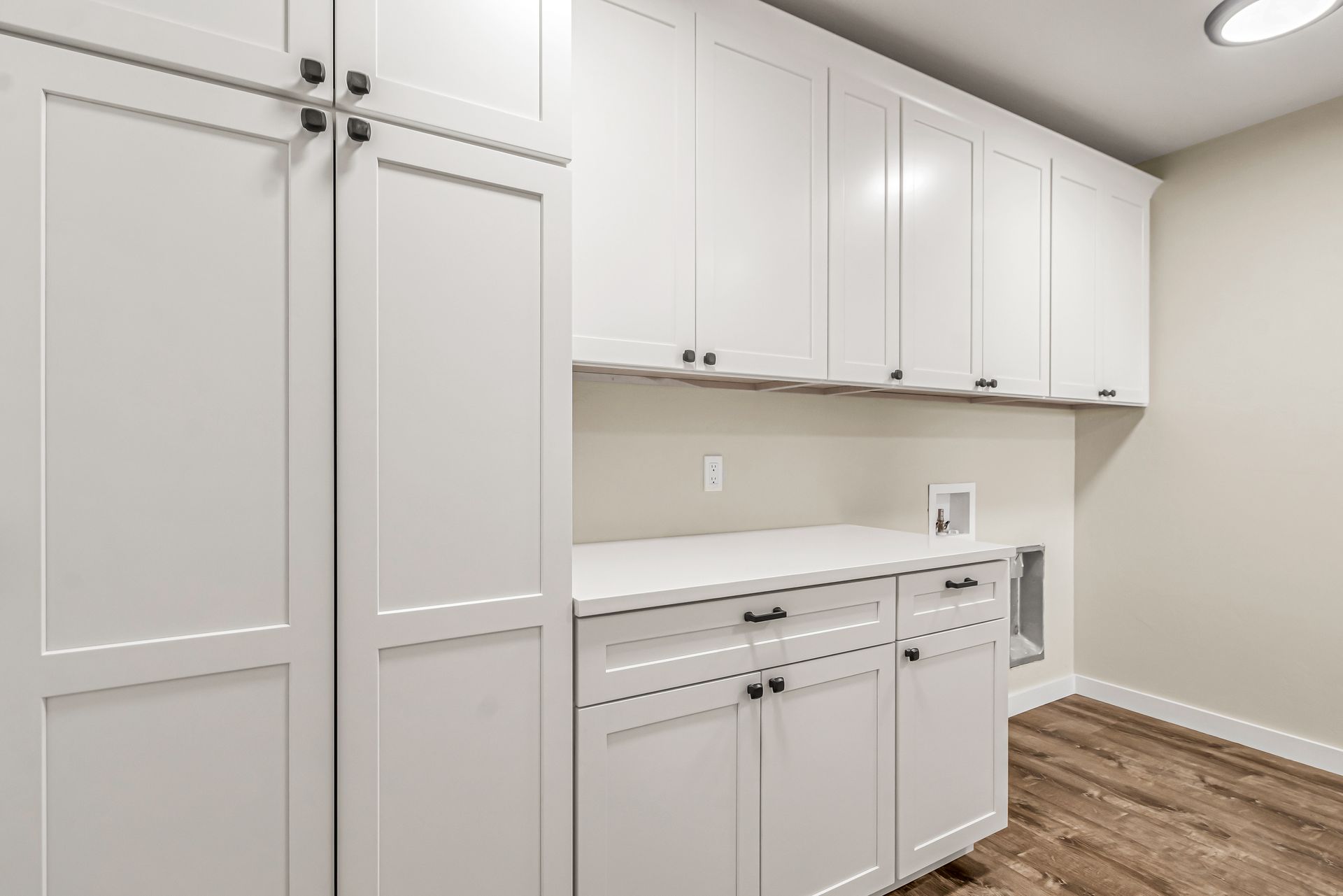 A laundry room with white cabinets and wooden floors.