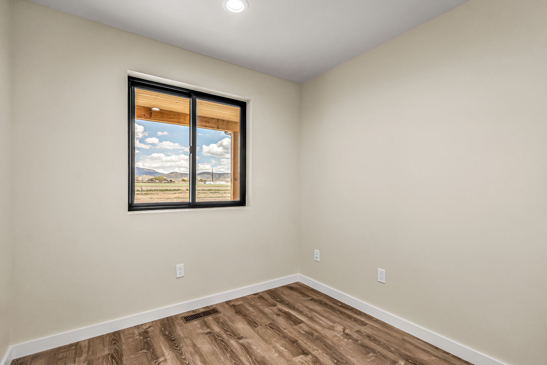 An empty bedroom with hardwood floors and a window.