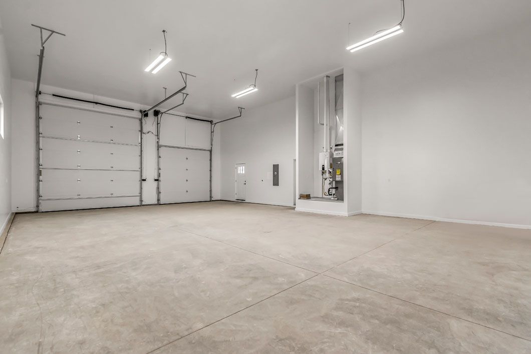 An empty garage with two garage doors and a concrete floor.