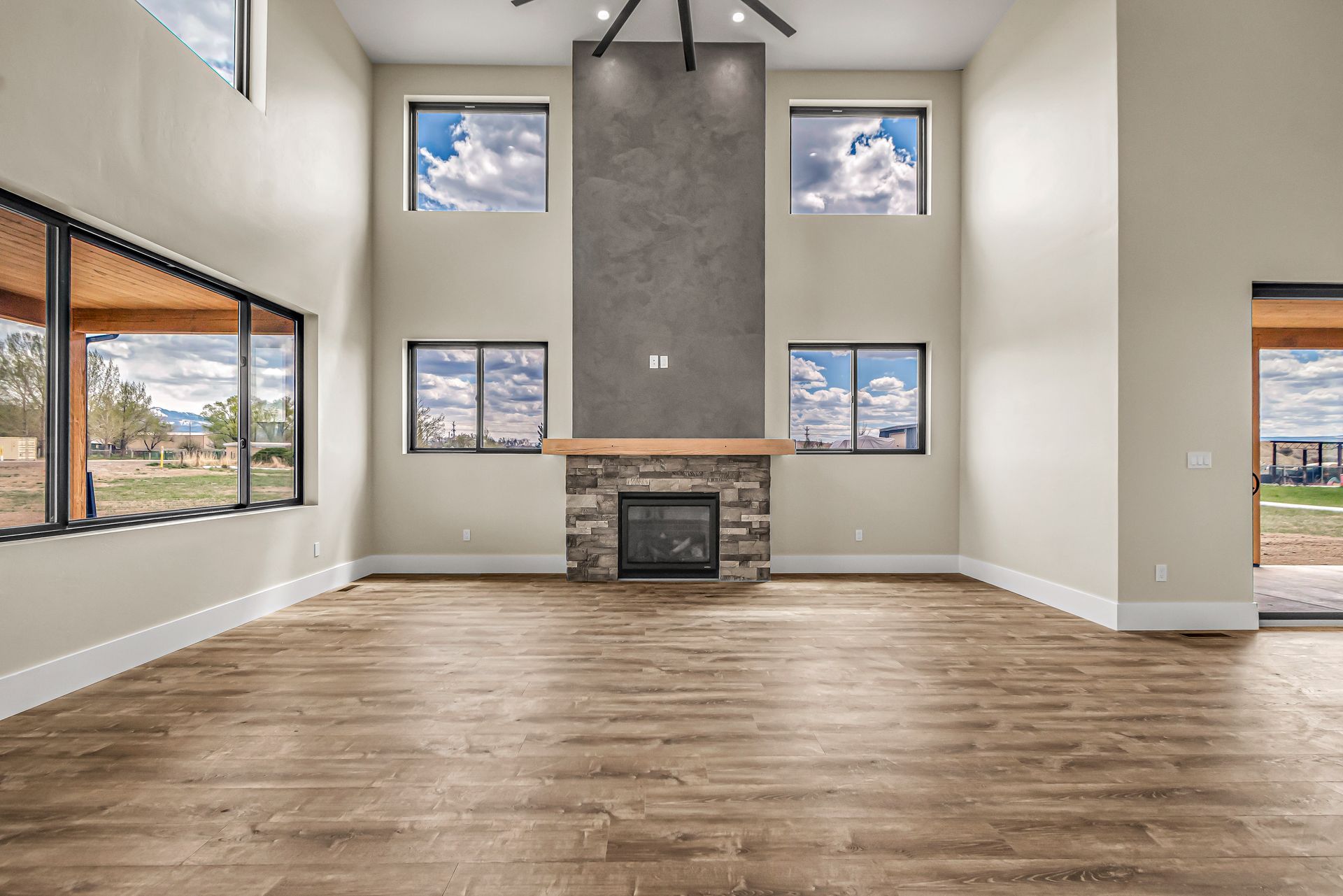 An empty living room with a fireplace and lots of windows.