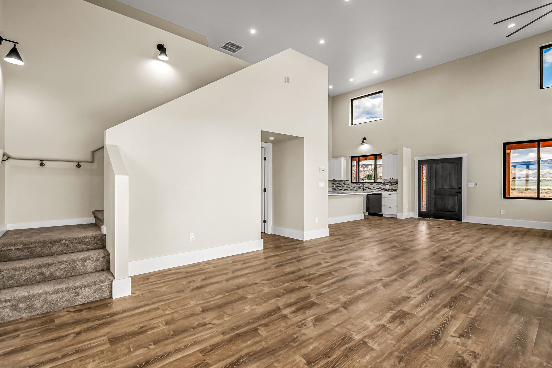 An empty living room with hardwood floors and stairs leading up to the second floor.