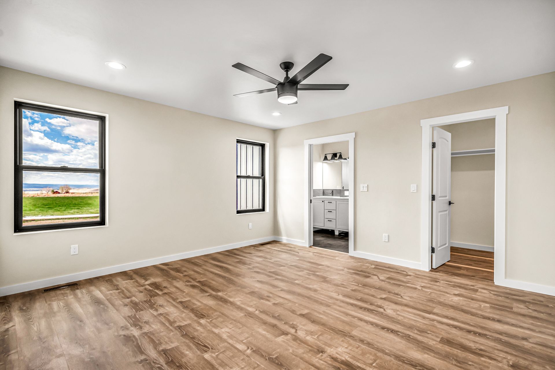 An empty bedroom with hardwood floors and a ceiling fan.