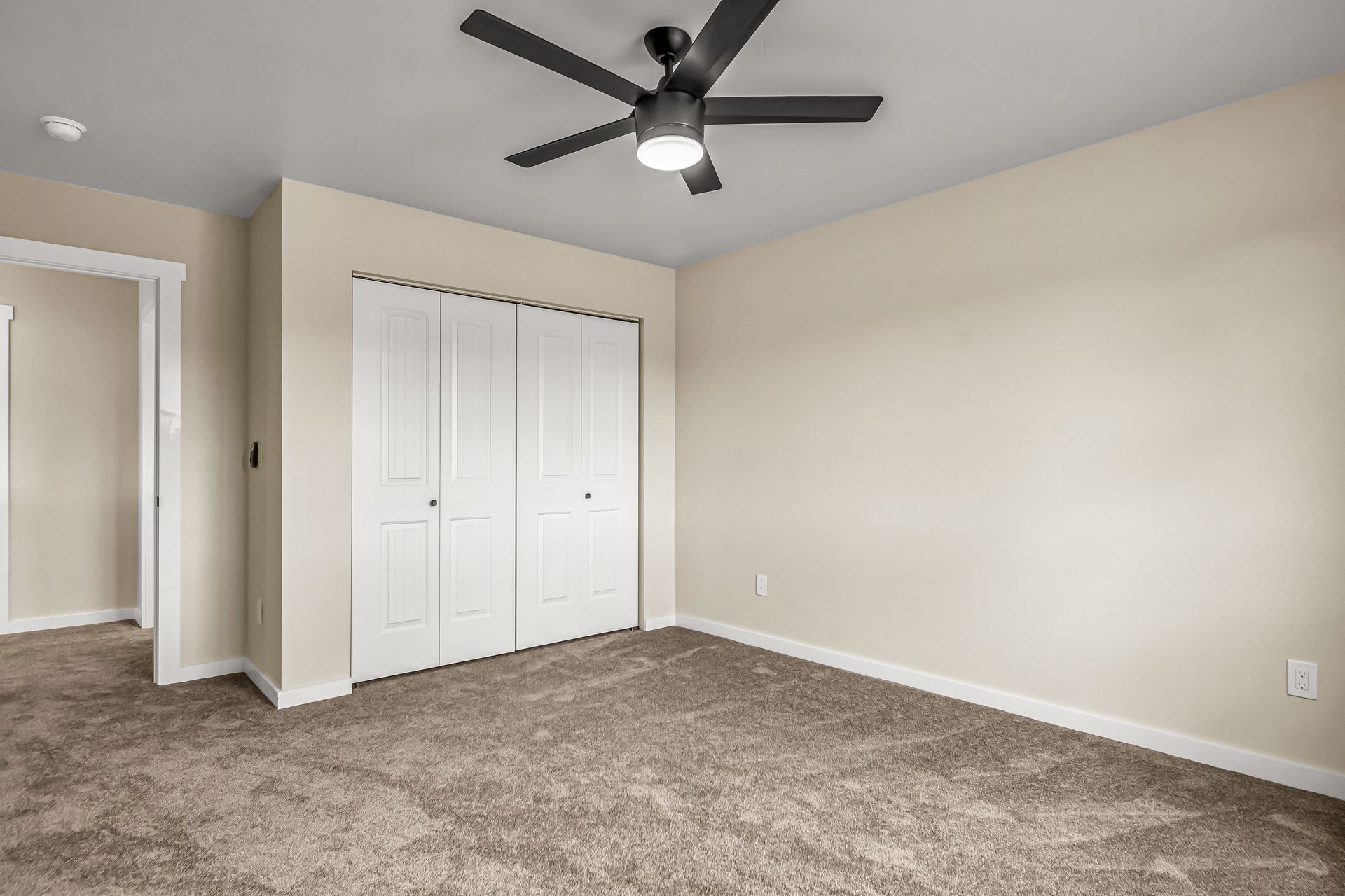 An empty bedroom with a ceiling fan and a closet.
