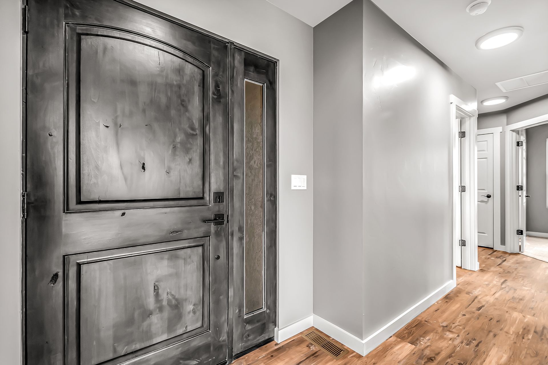 A hallway with hardwood floors and a large door.