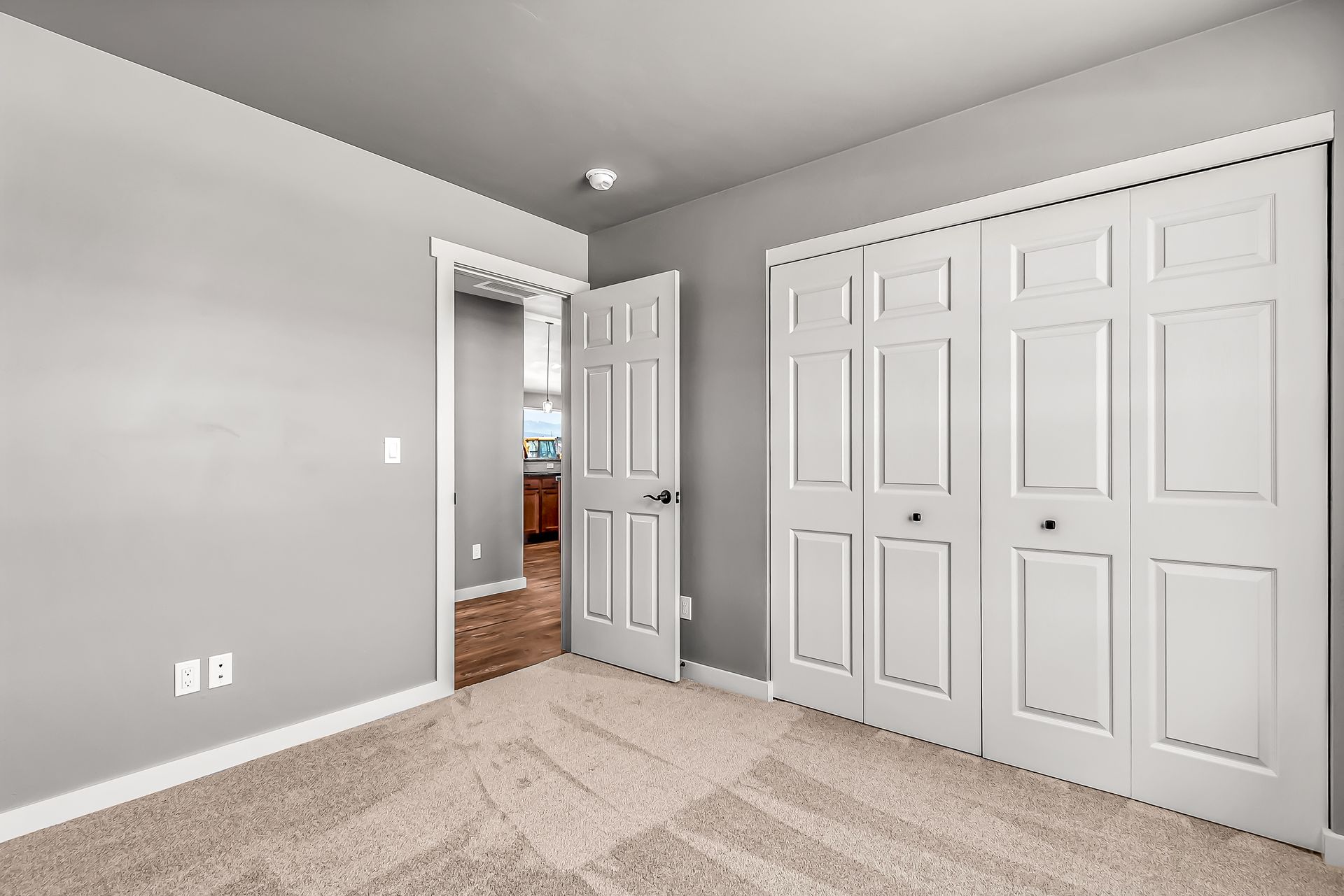 An empty bedroom with gray walls and white doors.