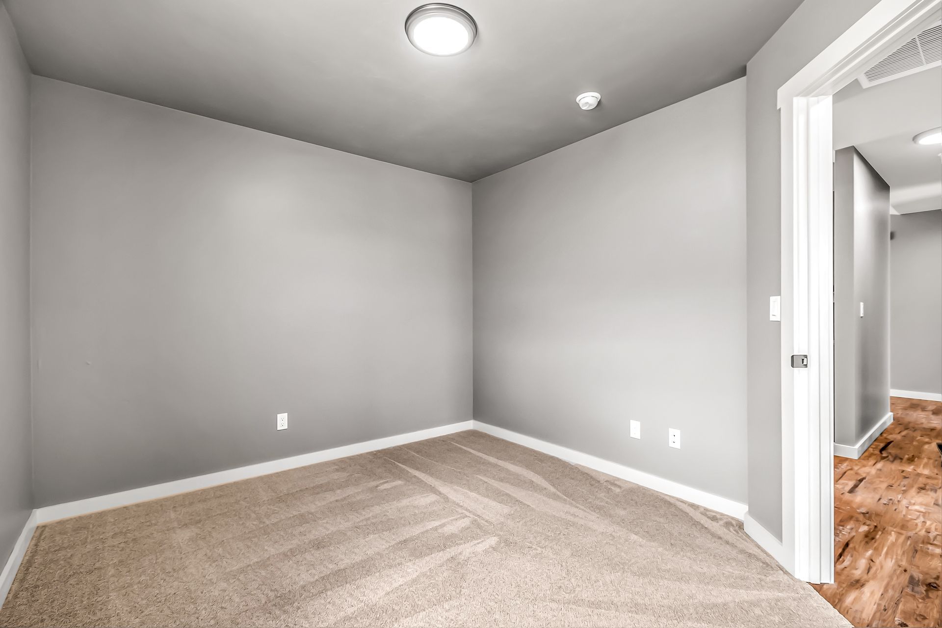 An empty room with a carpeted floor and gray walls.