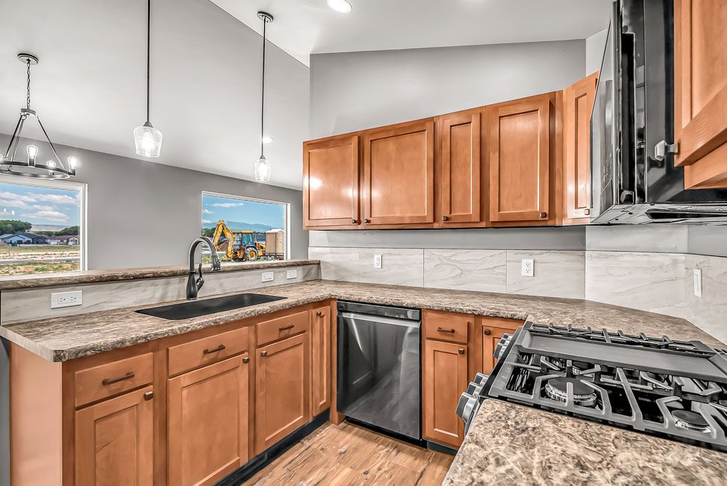 A kitchen with wooden cabinets , granite counter tops , stainless steel appliances and a stove top oven.