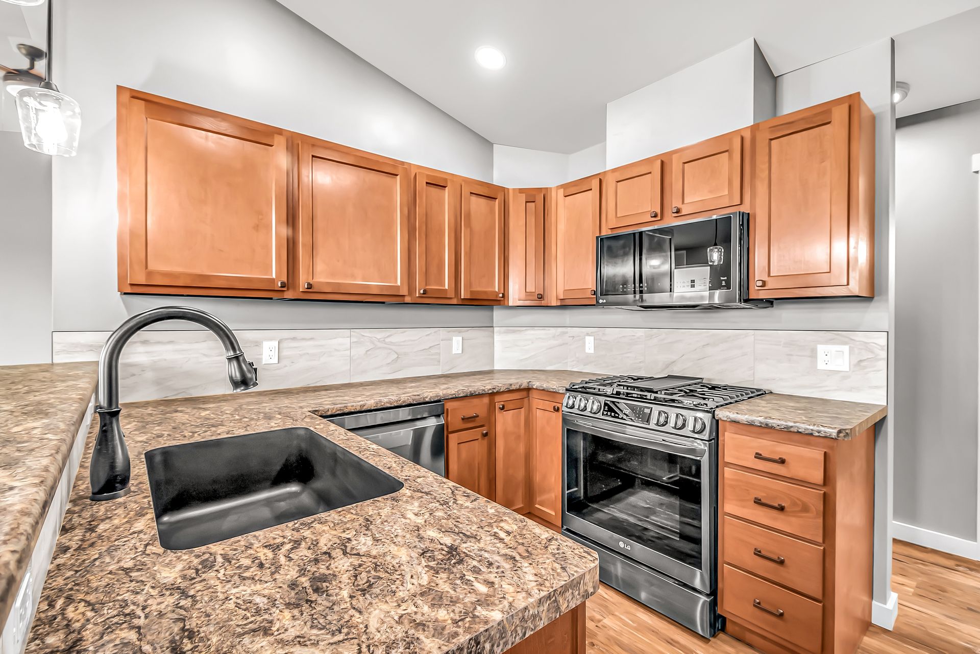 A kitchen with wooden cabinets , granite counter tops , stainless steel appliances and a stove.