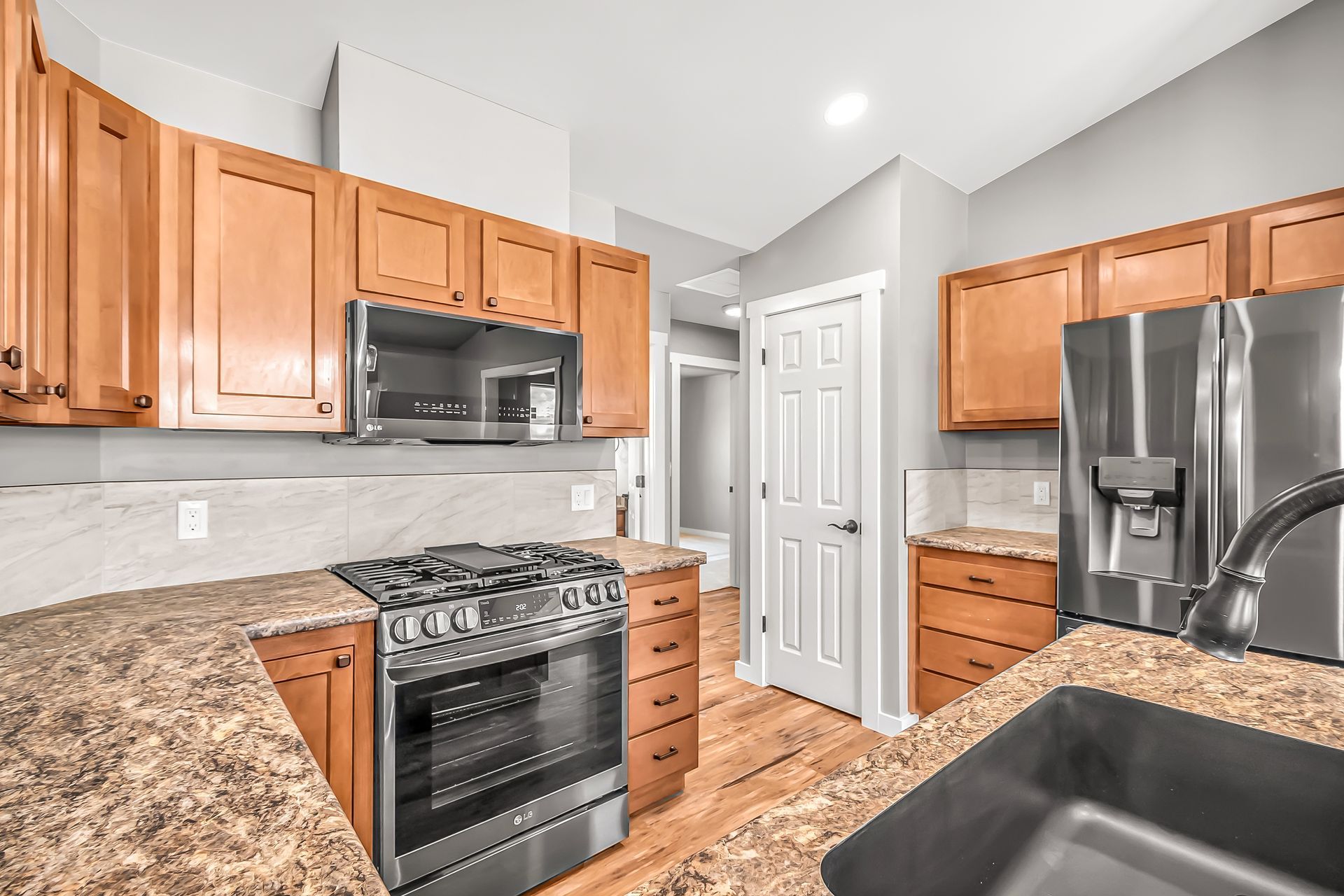 A kitchen with stainless steel appliances , granite counter tops , and wooden cabinets.