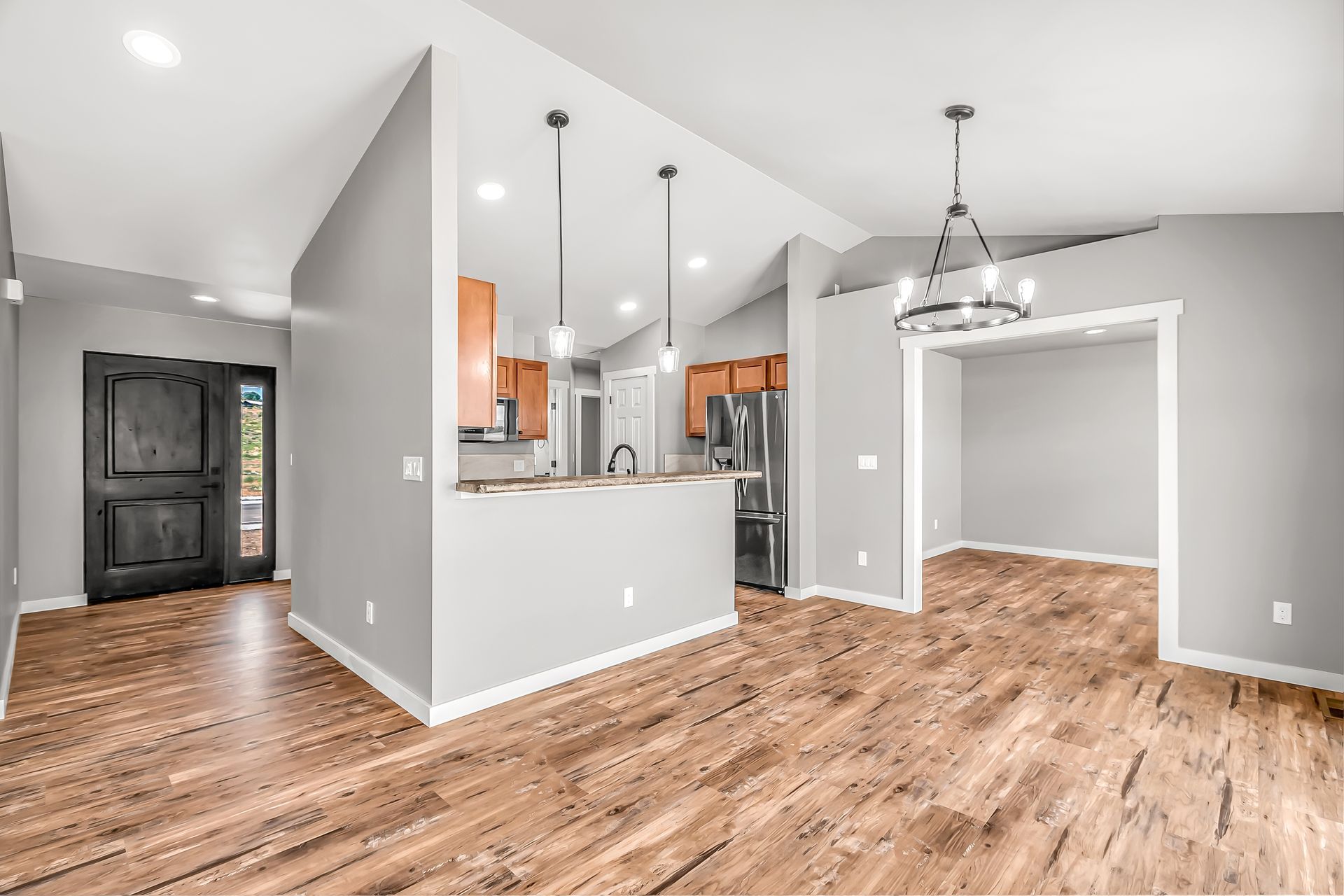 A living room with hardwood floors and a kitchen in the background.