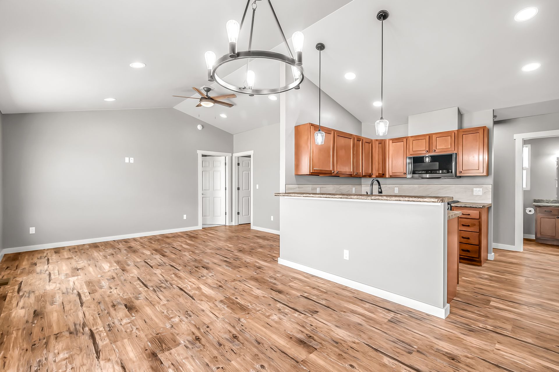 An empty kitchen with hardwood floors and a chandelier hanging from the ceiling.