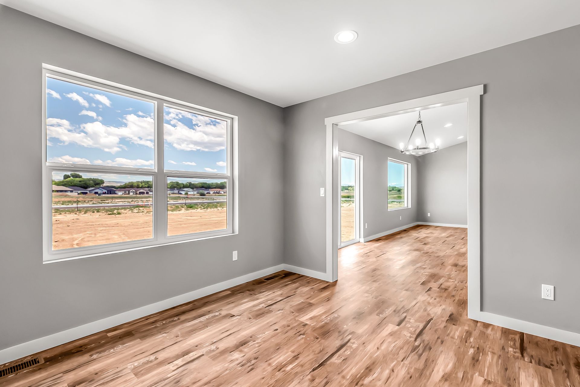 An empty living room with hardwood floors and two windows.