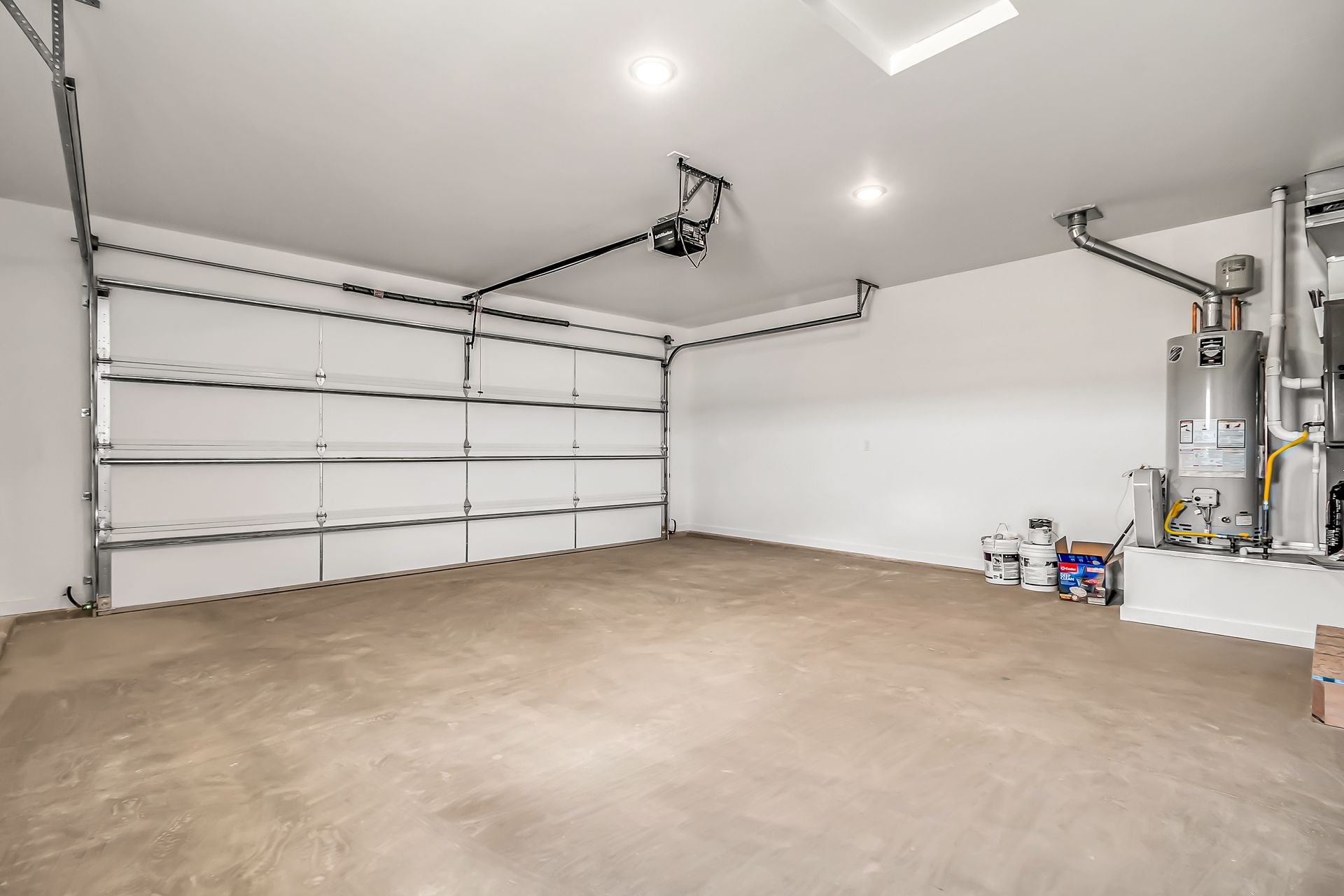 An empty garage with a garage door open and a water heater.