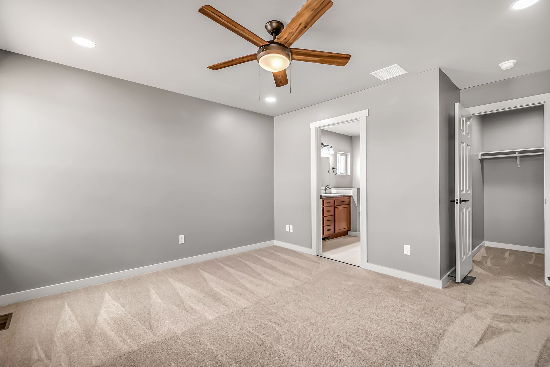 An empty bedroom with a ceiling fan and a walk in closet.