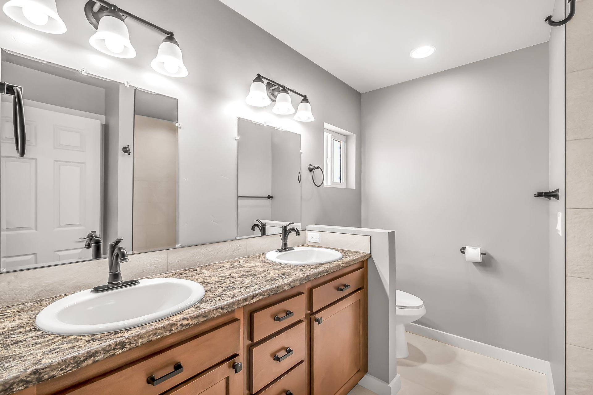 A bathroom with two sinks , a toilet and a mirror.