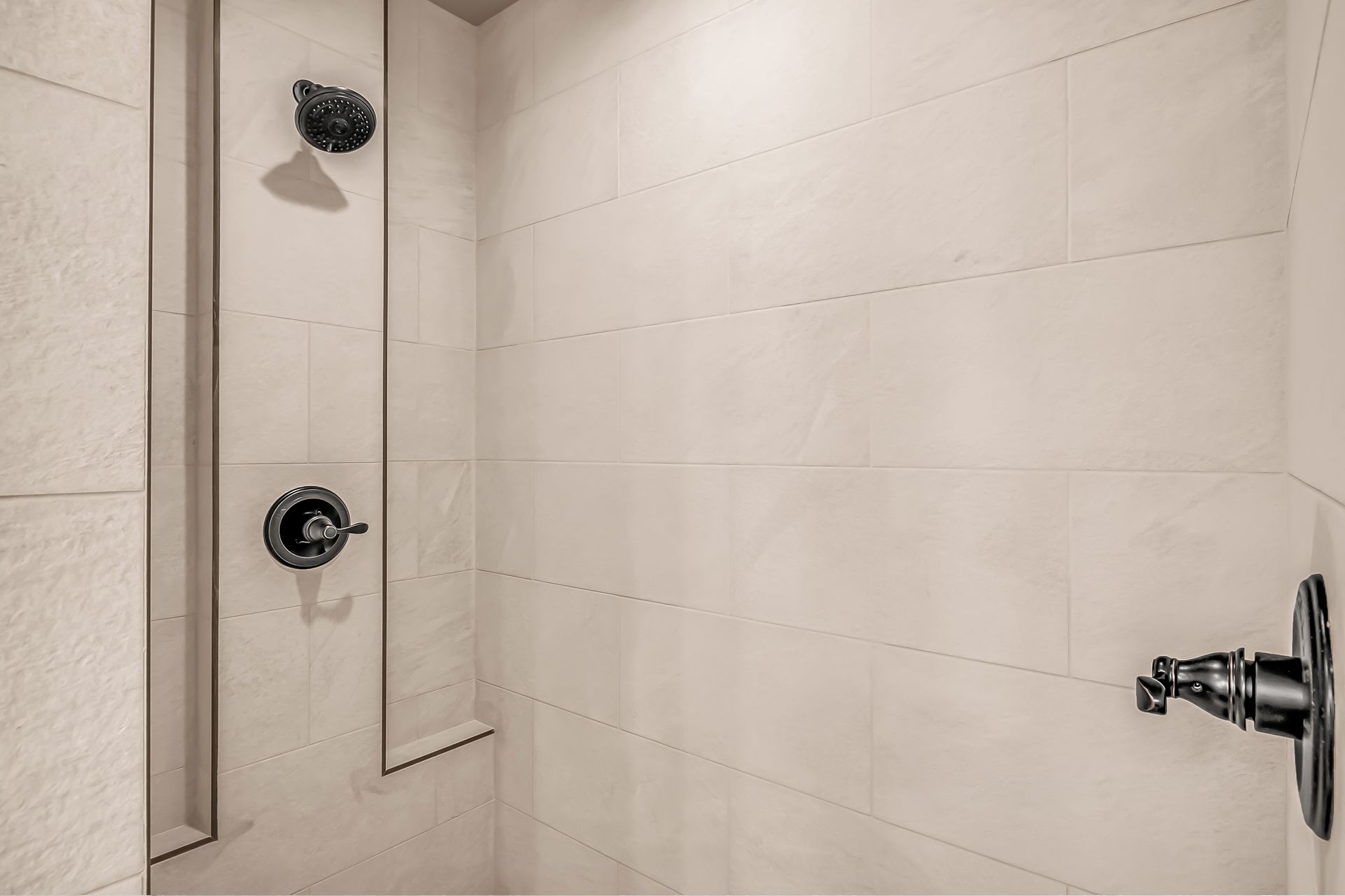 There is a shower with two shower heads on the wall.